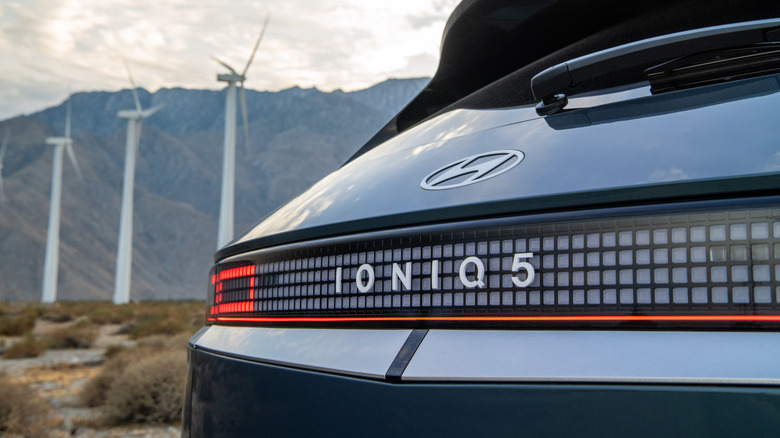 A rear image of a Hyundai Ioniq 5 EV with a wind farm in the background.