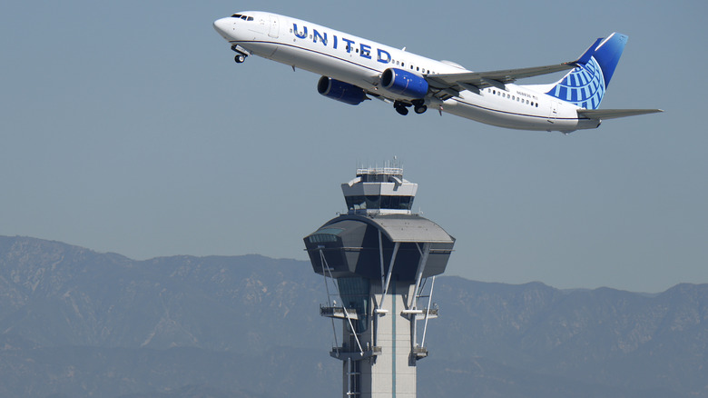A United Airlines plane flies over an air traffic control tower