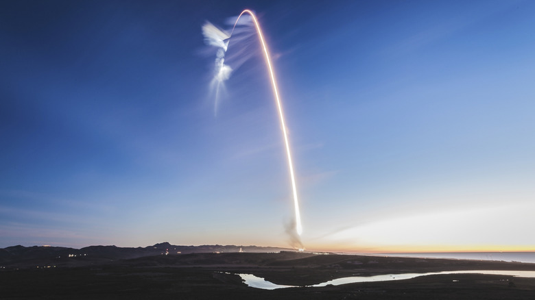 Launch trail of a SpaceX Falcon 9 rocket over rivers and hills