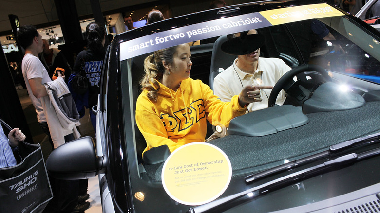 A college kid points something out on a car at the new york auto show