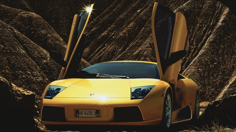 a yellow Lamborghini Murcielago parked in front of desert mountains