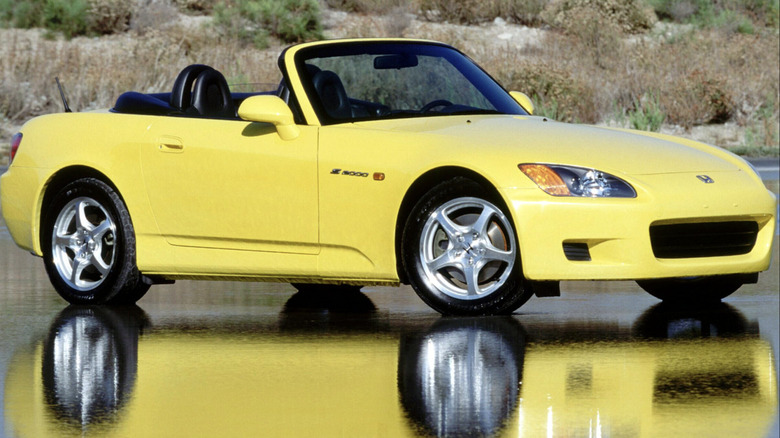 a yellow S2000 parked on a simmery reflective blacktop in the desert