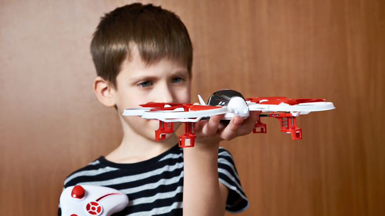 Little boy with a toy quadcopter drone at home