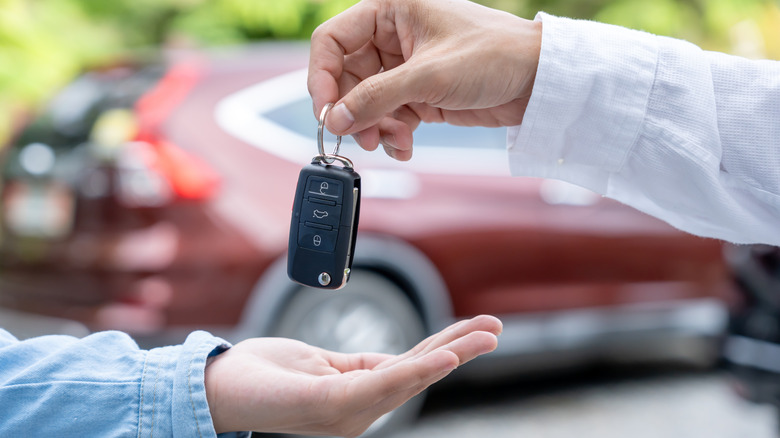 A car salesperson handing someone a car keyfob.