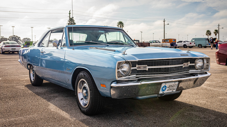 A light blue 1960s Dodge Dart parked in an outdoor car park.