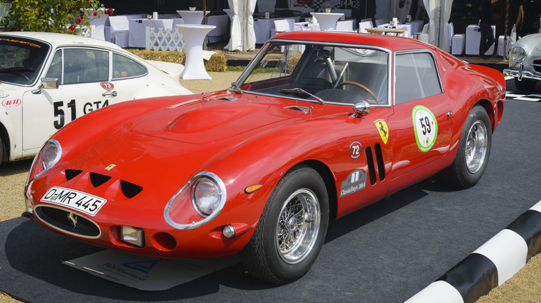 A race-spec red 1960s Ferrari 250 GTO parked on outdoor display.