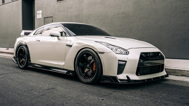A white Nissan R-35 GTR parked outside near a building.