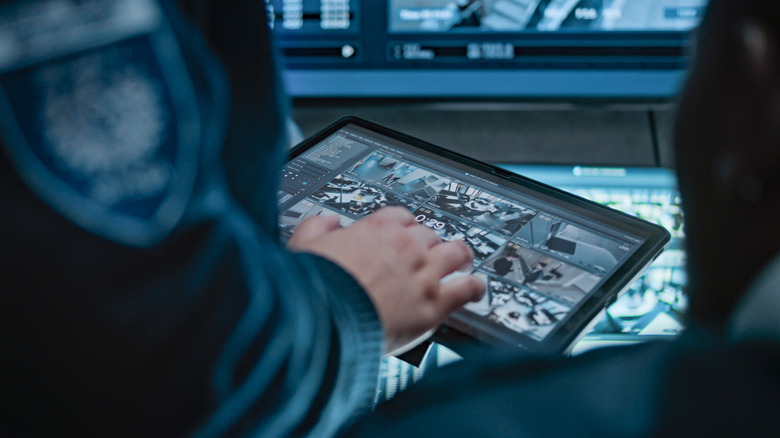 A police officer watching surveillance camera video on a tablet inside a data center