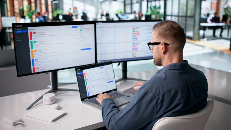 A man sitting at a desk looking at data on multiple computer screens