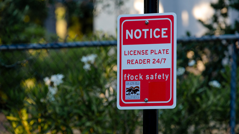 Sign on a Flock camera pole saying "Notice: license plate reader 24/7 Flock Safety"