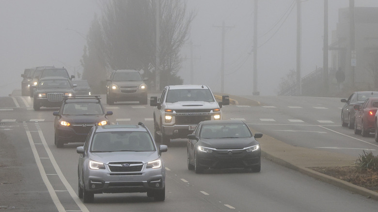 Cars driving on an urban street in foggy weather