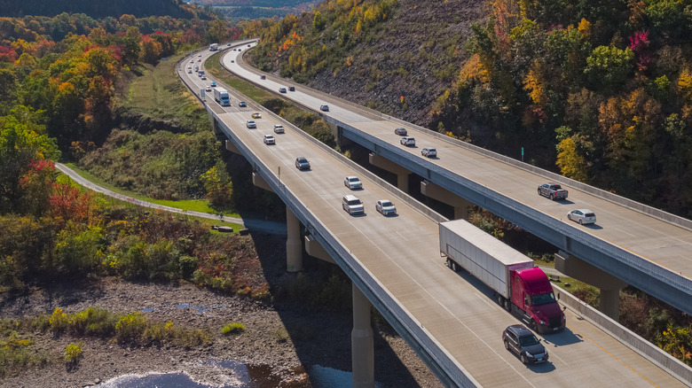 A busy highway bridge in a mountainous landscape with semi trucks and cars