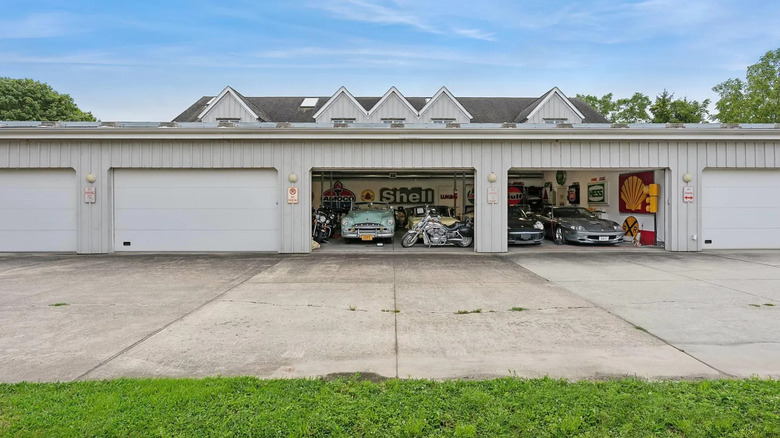 Two of five garage doors opened on a light gray garage revealing classic cars, motorcycles and auto memorabilia.