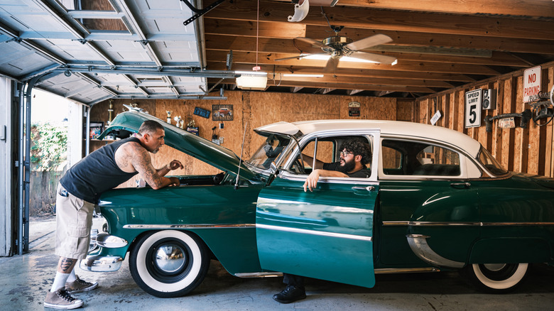 Two men trying to fix a classic car