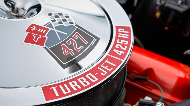 Closeup of silver air cleaner on an L72 Turbo-Jet 425 hp Chevrolet 427 Big Block V8 with red valve covers under the hood of a Corvette