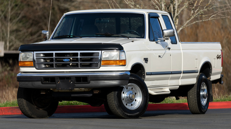1997 Ford F-250 XLT Super Duty pickup truck parked on a paved surface with bare trees in the background