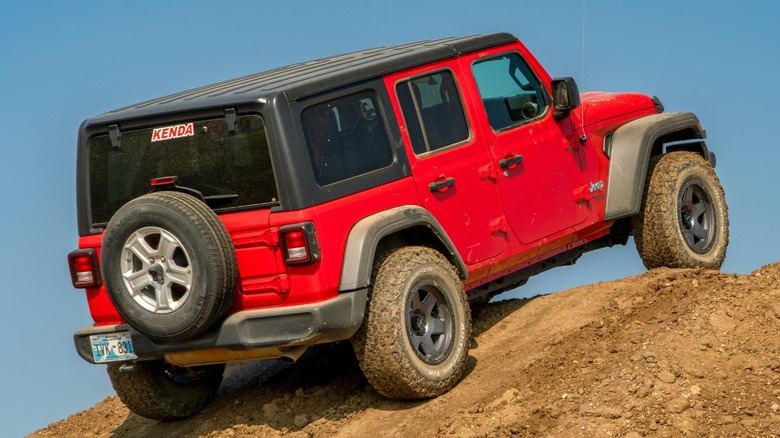2021 red Jeep Wrangler cresting a hill off road.