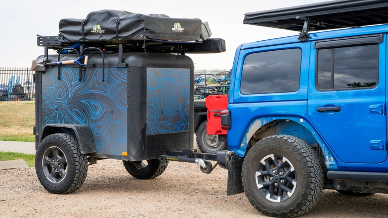 Jeep Wrangler towing a trailer with a roof-top tent