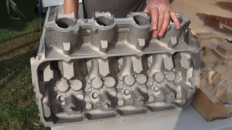 Person's hands resting on Ford's Calliope V8 engine.