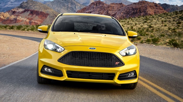 A yellow 2017 Ford Focus ST driving on a road through the desert