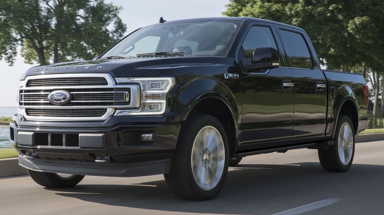 A black 2019 Ford F-150 driving on a road by a body of water