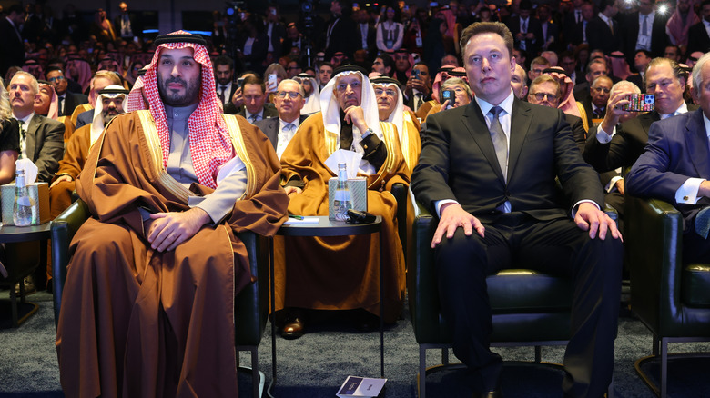 WASHINGTON, DC - NOVEMBER 19: Tesla CEO Elon Musk sits with Crown Prince and Prime Minister Mohammed bin Salman of Saudi Arabia as U.S. President Donald Trump delivers remarks at the U.S.-Saudi Investment Forum at the Kennedy Center on November 19, 2025 in Washington, DC. The forum is intended to bring together business leaders, innovators and political leaders with the goal of strengthening economic ties and promoting investment between the United States and Saudi Arabia.