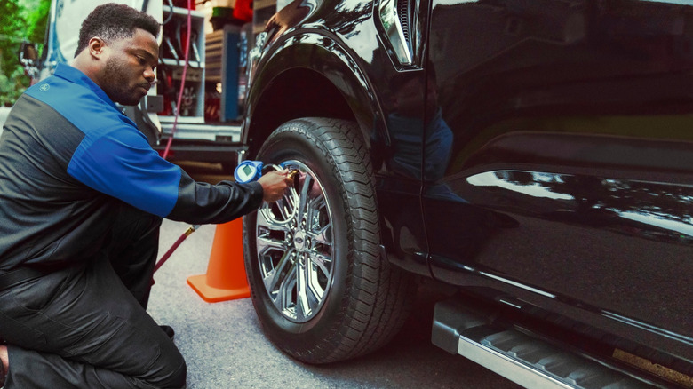 A Ford remote service technician shown checking tire pressure for a truck