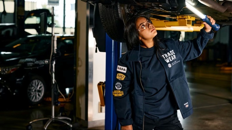An auto tech student seen working in a car that has been elevated on a lift