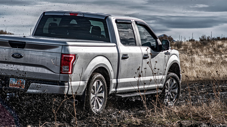 2015 Ford F-150 driving on a muddy road.