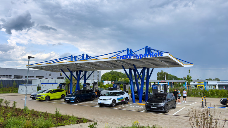 MÜNCHBERG, GERMANY - MAY 24: Modern electric vehicle charging hub of ENBW for electric cars at Euro Rastplatz Münchberg Nord with a large canopy, several cars plugged in, and people nearby under an overcast sky on May 24, 2026 in Münchberg, Germany. (Photo by EyesWideOpen/Getty Images)