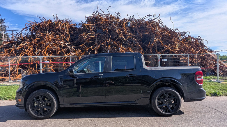 A black Ford Maverick Lobo parked in front of a pile of rusty rebar