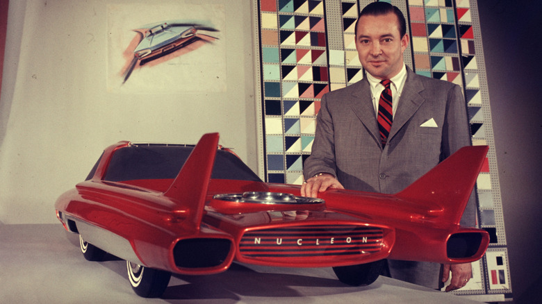 A man posing with the later scale model of the Ford Nucleon in red and white.