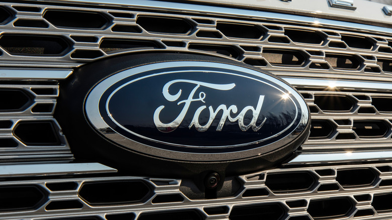 A close-up of the Ford logo on the front grille of a Ford Explorer PHEV.