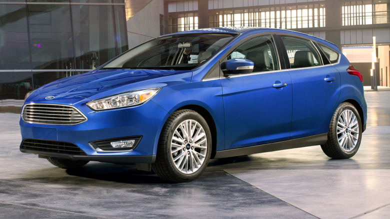 Front three quarters shot of a blue Ford Focus hatchback parked in front of buildings
