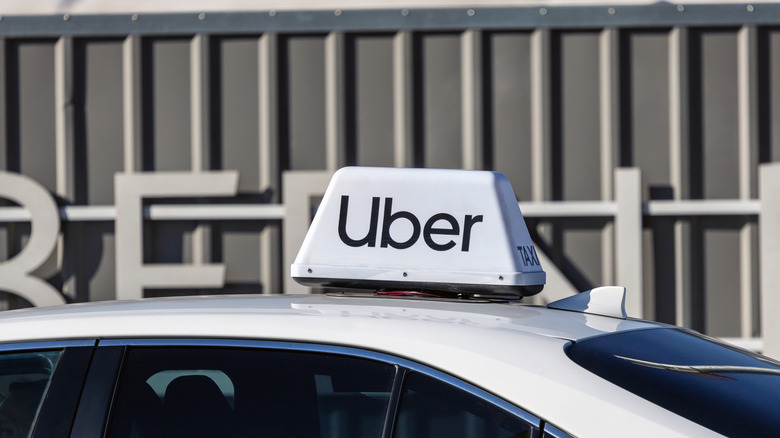 Warsaw, Poland - February 15, 2025: Uber logo sign on top of passenger taxi car. Cab transport service, ridesharing company logotype, brand signboard with inscription.