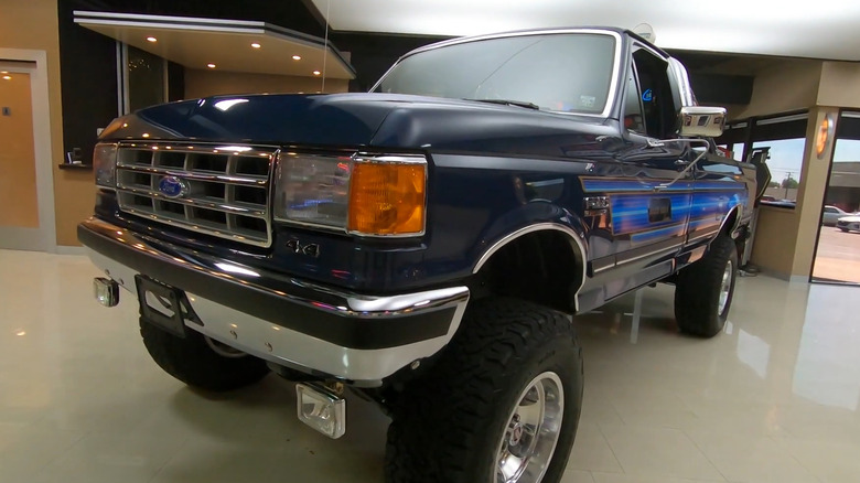 A Ford Bigfoot Cruiser dominates a showroom with a lift kit and striking blue paint.