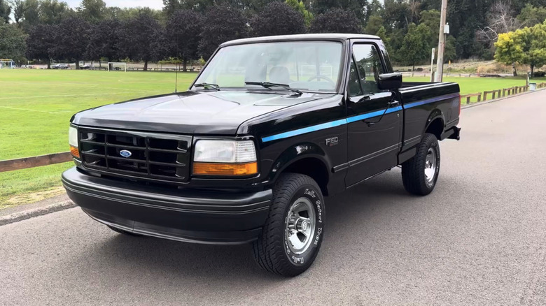 A black Ford F-150 Nite gleams in the daylight with a contrasting blue stripe.