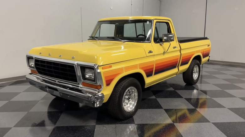 A yellow Ford Free Wheeling truck sits on a checkered floor sporting unique side stripes.