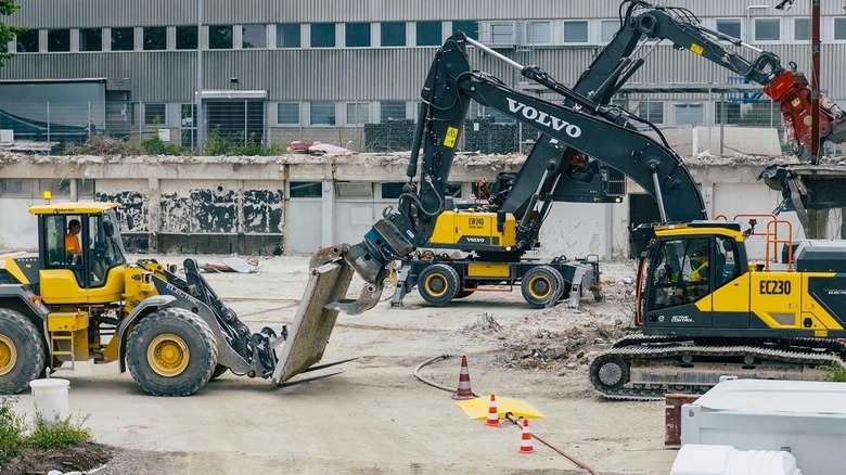 Three Volvo Construction Equipment electric machines working to demolish a building on the Siemens campus.