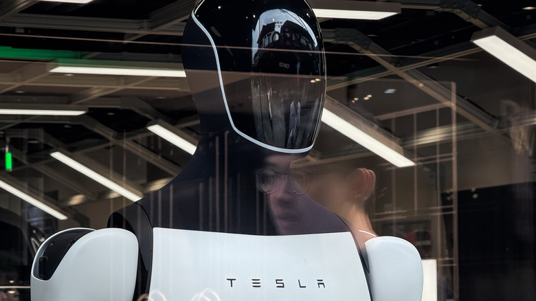A Tesla Optimus robot, seen from the front through a window.