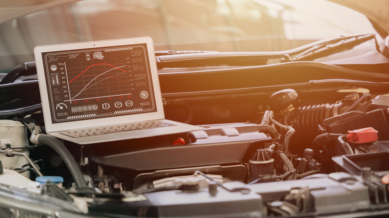 A white laptop placed on top of an engine bay, symbolizing an ECU tune, with the sun in the background.