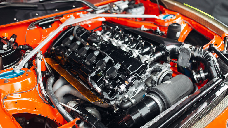 A close-up of the engine bay in an orange, heavily tuned performance car.