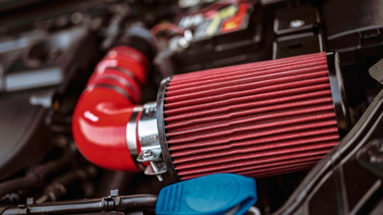 A close-up image of a red cold air intake installed in a car's engine bay