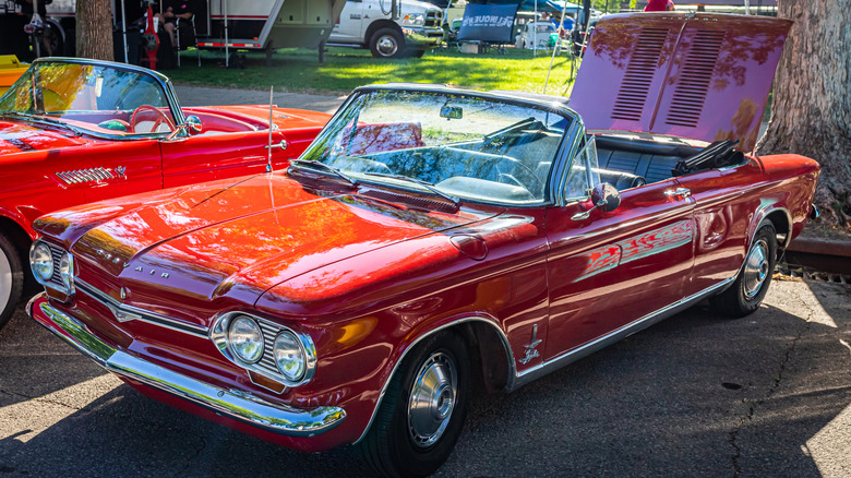 A red 1965 Chevrolet Corvair Monza Spyder Turbo with its top down and its trunk up.