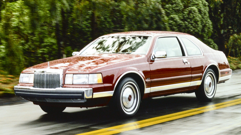 A red 1985 Lincoln Continental Mark VII in motion.