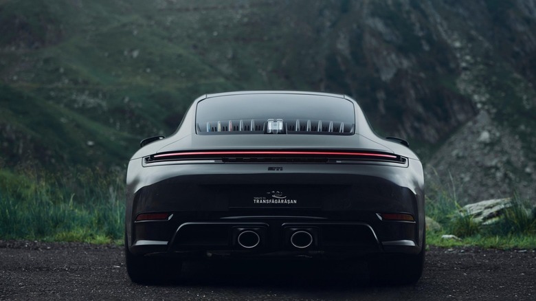 A 2025 Porsche 911 parked in dirt by a mountain