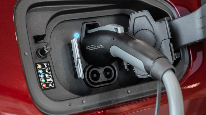 A plug-in hybrid charging port with a cord plugged in and charging.