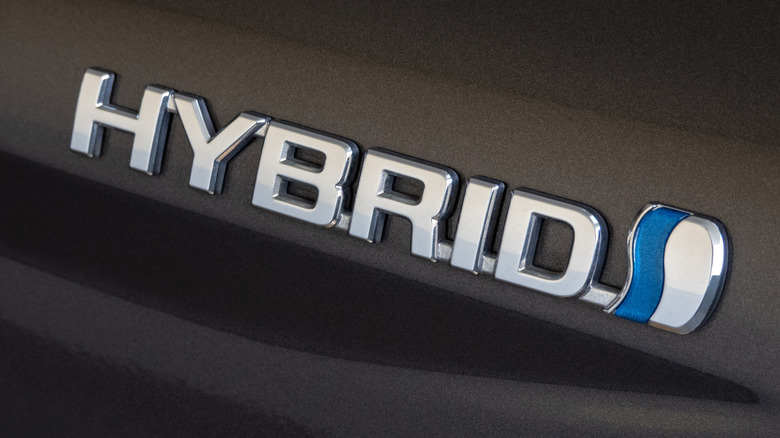 A Hybrid badge on a dark colored vehicle.