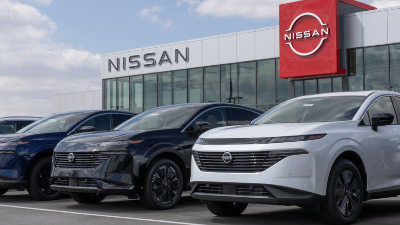 Nissans parked in front of a Nissan dealership