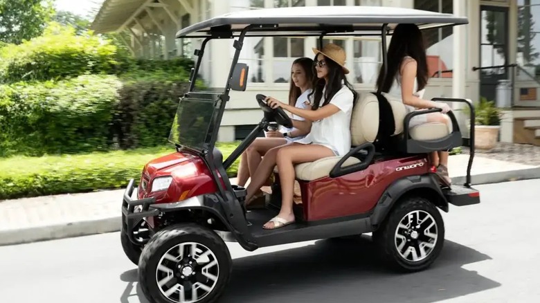 A group of people driving a ClubCar golf cart